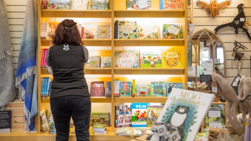 A shop assistant restacks the children's bookshelves in the gift shop at Dyffryn Gardens, Vale of Glamorgan